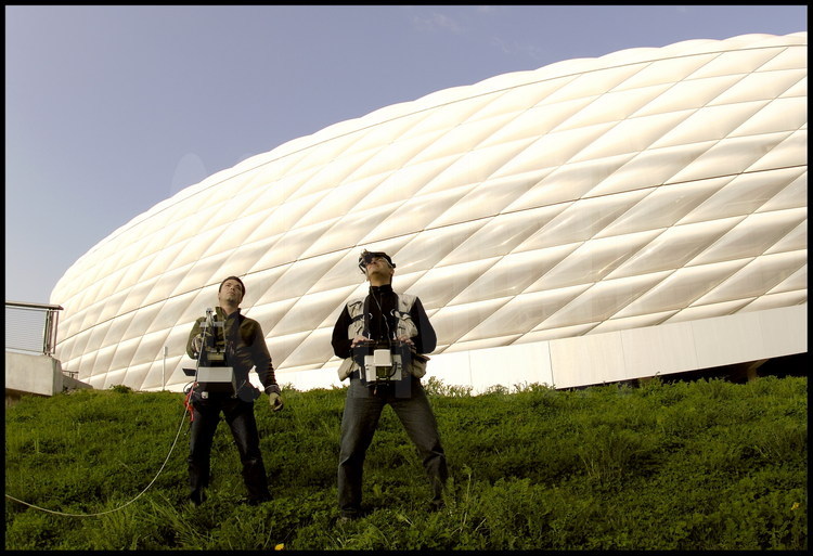 Le photographe Stéphane Compoint et son assistant Xavier Defaix en situation de prise de vue aérienne au dessus du stade de Munich à l’aide de leur ballon à hélium radio-commandé depuis le sol.
