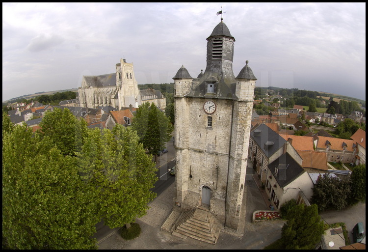 De Saint-Riquier, on connaît surtout l’abbaye, célèbre pour le festival de musique classique programmé chaque été. Le beffroi est plus discret et plus sobre, moins imposant avec ses dix-huit mètres de haut, il se situe à l’écart. À la base de cette tour carrée en grès, une plaque indique que Jeanne d’Arc, prisonnière et conduite à Rouen pour y être jugée puis brûlée, passa à cet endroit en novembre 1430. Construit en 1283, le beffroi a subi au fil des siècles de multiples transformations. Le sous-sol, qui abritait autrefois le cachot, a été comblé. Le rez-de-chaussée accueille aujourd’hui le syndicat d’initiative. À l’étage supérieur, une autre pièce fait office de grenier. On y a stocké d’anciens instruments de la fanfare communale, aujourd’hui disparue... ainsi que les photos officielles des anciens présidents de la République, de Coty à Mitterrand. Au second, la pièce est vide mais la vue sur le village imprenable. Le troisième niveau conserve l’ancien mécanisme de la cloche, quatre fois centenaire, électrifiée en 1968. Cette cloche, il faut terminer l’ascension par une échelle pour y accéder.