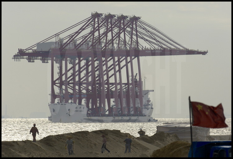 Situé sur la rive sud de l’île de Changxing Dao, près du village de Zhenhua, la manufacture d’équipement portuaires du ZPMC (Zhenhua Port Machine Company). Cette entreprise a exporté en 2005 plus de 1500 portiques dans 70 ports de 37 pays, ce qui représente près de 60% du marché mondial. C’est d’ailleurs cette compagnie qui a fourni les portiques pour les nouveaux quais du port du Havre, en France, destinés à accueillir les porte-containers géants de 8000 EVP et plus. Ici, un navire, spécialement conçu pour cet usage, appareille pour livrer quatre portiques géants au port chinois de Ningbo, 200 km au sud de Shanghai.