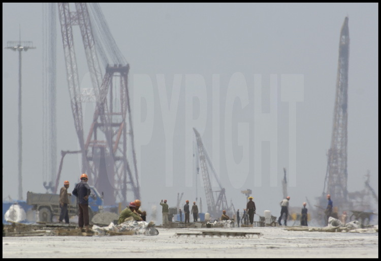 Juin 2005. Ouvriers au travail sur la dalle de béton de 720000 mètres carrés -soutenue par 2819 piliers- de la première tranche des travaux du port en eaux profondes de Yangshan.