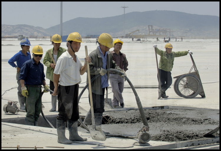 Juin 2005. Ouvriers au travail sur la dalle de béton de 720000 mètres carrés -soutenue par 2819 piliers de soutènement- de la première tranche des travaux du port en eaux profondes de Yangshan.