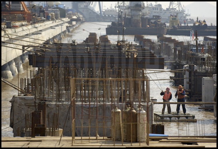 Novembre 2005. Les ouvriers ont commencé à installer les piliers de soutènement de la deuxième phase de travaux du port de Yangshan, gagnée elle aussi sur la mer. Située juste au sud de la première, cette nouvelle tranche sera opérationnelle dès la fin de l'année 2006.