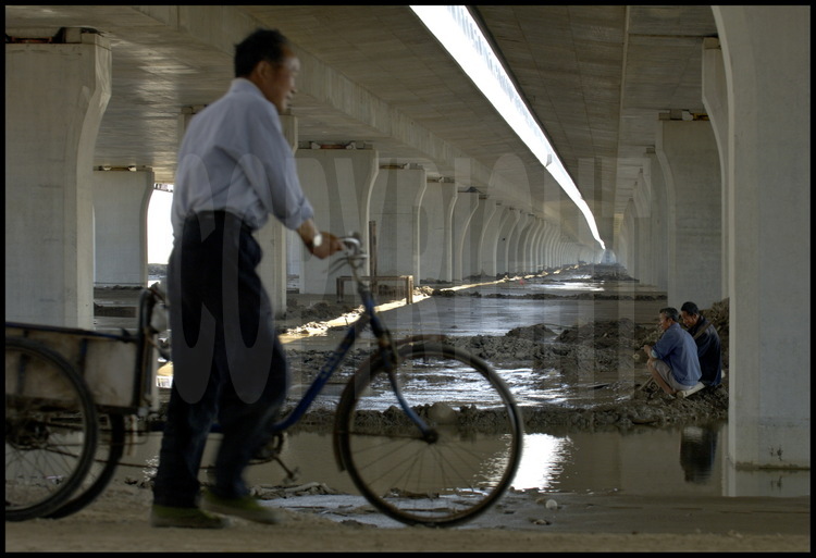 Juin 2005. Sous le pont de Donghai à hauteur du point kilométrique 1. Fin de journée pour cet ouvrier du chantier. En arrière plan, l’élévation 1, distante de cinq kilomètres.
