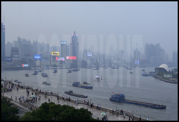 Au beau milieu du centre ville de Shanghai à la nuit tombante, trafic de péniches et navires le long de la Huang Pu river. Au premier plan, les nouveaux quais surélevés du Bund, lieu de promenade favori des shanghaiens depuis près d'un siècle.