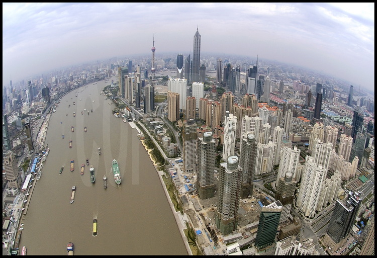 Le centre ville de Shanghai vu depuis la Huang Pu river, avec son trafic de navires et péniches de tout tonnage. Sur la rive droite, la ville nouvelle de Pudong (qui signifie « à l’est du Pu») dominée par la tour TV « Perle de l’Orient » à gauche et la tour Jinmao à droite.