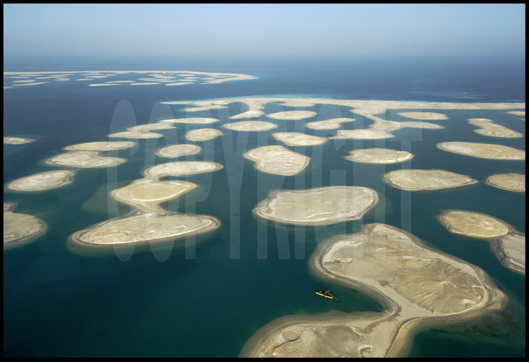 June 2006. Located 4 km from the coast, this enormous off-shore site is a group of 300 small artificial islands laid out to represent our planet’s continents and main islands.  Each island will cover 2 to 8 hectares and will be 50 to 100 meters from its neighbor.  Surrounded by an oval dyke, the archipelago will span a width of 8 km and a length of 6km.  The embankment work should be finished at the end of 2006.  The sample island and its villa are surrounded by North America and Greenland.  Below, North America and the ridge of the Andes mountain range face Africa.  Asia is coming along nicely but Europe, South East Asia and Oceania have barely emerged.  The “France” island will have a surface area of 4 hectares.  The “Australia” island has already been sold to a Kuwaiti real estate company.  The “Spain” island has already been sold to Spanish brand name “Zara” owner.  Each island is sold between 7.5 and 36 million dollars depending on its surface.  The entire project has cost nearly 2 billion dollars.