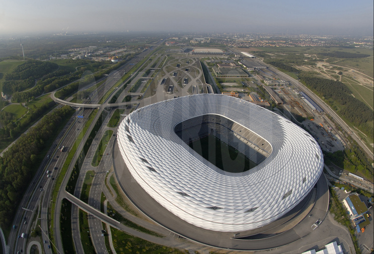 Munich : Alors que le  stade olympique avait en son temps été salué pour son audace architecturale, nul doute que Le Munchner stadion, d’une capacité de  66000 places couvertes, va lui aussi faire parlé de lui avec sa structure de membrane à coussin d’air, réellement innovante, qui le font ressembler à un gigantesque cocon flottant. En arrière plan, la ville de Munich.
