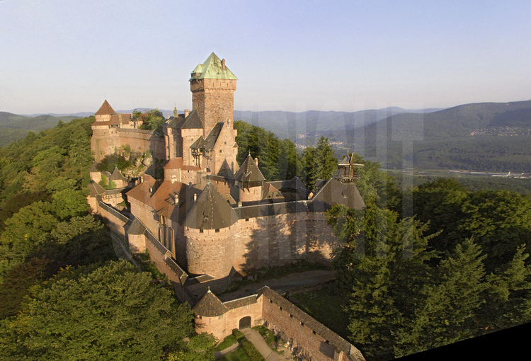 Vue aérienne du de la façade est du château du Haut-Kœnigsbourg. Dominant la plaine d'Alsace à une altitude de 755 m, le château du Haut-Kœnigsbourg est l'un des sites touristiques les plus fréquentés en France, avec près de 500 000 visiteurs par an. Appartenant à l'État français depuis 1919, le site fut transféré par l'État au Conseil général du Bas-Rhin en janvier 2007 (transfert qui fut le premier bien patrimonial transféré par l'État parmi une liste de 176).