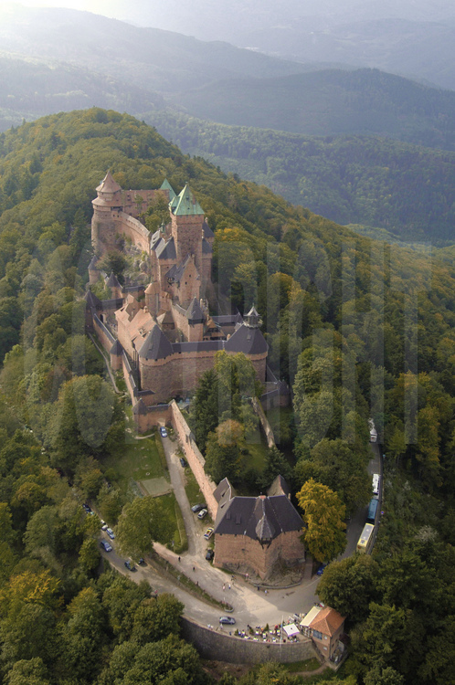 Vue aérienne du de la façade est du château du Haut-Kœnigsbourg. Dominant la plaine d'Alsace à une altitude de 755 m, le château du Haut-Kœnigsbourg est l'un des sites touristiques les plus fréquentés en France, avec près de 500 000 visiteurs par an. Appartenant à l'État français depuis 1919, le site fut transféré par l'État au Conseil général du Bas-Rhin en janvier 2007 (transfert qui fut le premier bien patrimonial transféré par l'État parmi une liste de 176).