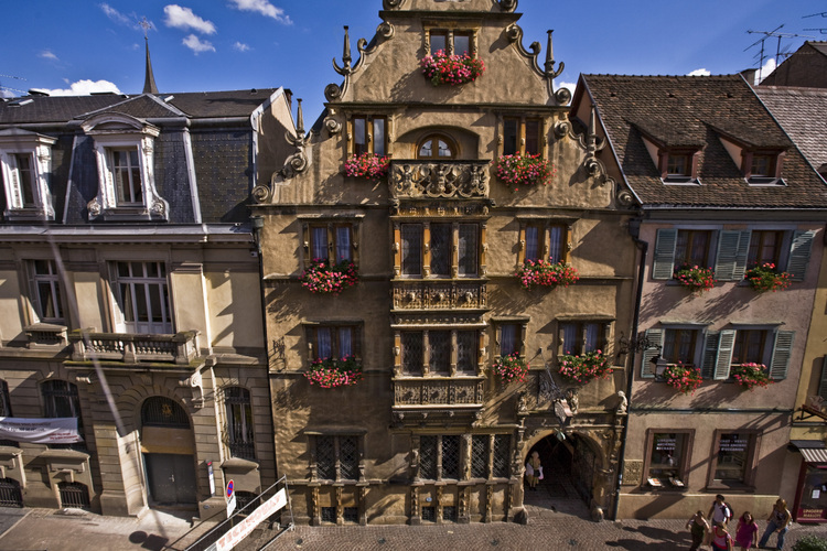 Centre historique. Façade de la Maison des Têtes. Construite en 1609 pour le compte du marchand Anton Burger, cet édifice de la Renaissance allemande est l'un des plus célèbre de Colmar. Il doit son nom aux têtes ou masques grotesques qui ornent une riche façade sur laquelle s'élève un oriel de trois étages. Altitude 15 m.