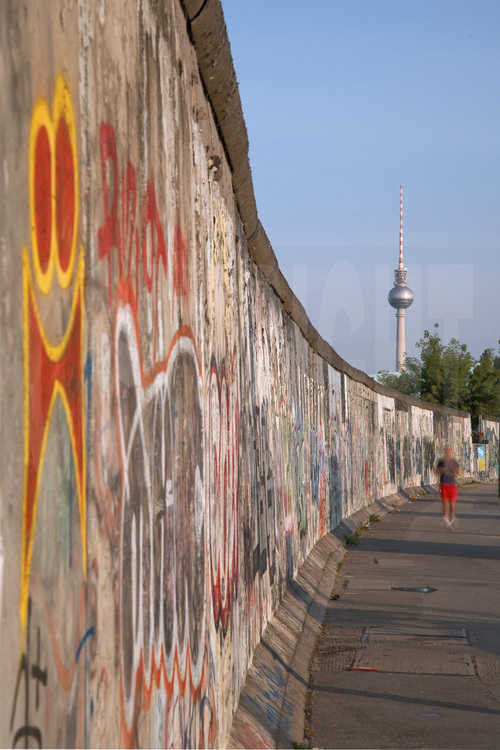 L’East Side Gallery. Située sur la Mühlenstrasse, dans le quartier de Friedrichshain, c’est le plus grand segment de mur conservé. Long de 1300 mètres et classé monument historique en 1992, c’est également devenu la plus grande galerie en plein air au monde. Avant 1989, le mur était de couleur blanche et grise, une barrière empêchait de l’approcher ou de le toucher. L’intégralité du fleuve, qui faisait office de «no man’s land», faisait partie de Berlin-Est et était arpenté par les patrouilleurs des gardes-frontières. De nombreux berlinois périrent noyés en tentant de passer à l’ouest. A cette époque, la Mühlenstraße faisait partie de l’itinéraire «protocolaire» des dirigeant est berlinois, entre le centre ville et l’aéroport de Schönefeld. C’est pourquoi elle fut délimitée par un segment de mur extérieur (appelé «mur occidental» par les autorités de RDA), afin de cacher le No Man’s Land. L’autre partie du mur se dressait le long de la berge, ces derniers dissimulant le dispositif habituel comprenant la clôture de signalisation, le chemin de ronde, les pylônes d’éclairage ainsi que des barbelés près de l’eau. Après la chute du mur, 118 artistes originaires de 21 pays commencèrent à peindre une gigantesque fresque sur la face est du mur, intouchée du temps de l'Allemagne divisée. Certaines de ces œuvres sont depuis devenues des icônes, tel le baiser échangé entre Leonid Brejnev et le dirigeant de la RDA Erich Honecker et la série de «dialogues» du français Thierry Noir. Mais en vingt ans, la pollution, les graffitis et l’usure du temps avaient failli détruire à jamais ces peintures, qui ont pris depuis une valeur patrimoniale considérable. C’est pourquoi la ville de Berlin a pris l’initiative de convier, durant l’été 2009, quarante artistes de l'époque, venus du monde entier, qui ont été invités cet été à reproduire trait pour trait leur œuvre telle qu’ils l’avaient crée il y a vingt ans. Le message de cette œuvre d’art urbain est celui de l’euphorie qui régna au lendemain de la chute du mur.
