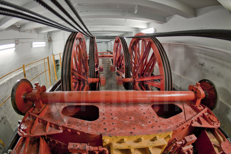 Au sous-sol du pilier est de la Tour Eiffel, la machinerie d'ascenseur de 1889, toujours en fonctionnement. En rouge, l'un des chariots du système (voir image n° 106).