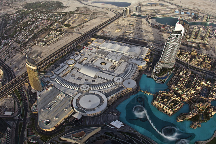 Aerial view of Dubai Mall, largest commercial center in the world. on the background, the shadow of the Burj Khalifa tower (highest in the world with 828 meters). On the right, the Address Hotel, a 5-star one with 58 floors as the Tour Montparnasse in Paris.