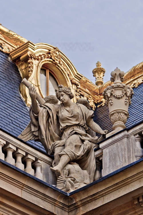 Derrière cette statue allégorique de la Victoire, juchée sur la balustrade nord de la cour de Marbre, la toiture en ardoise, un matériau considéré comme plus chic que la tuile.