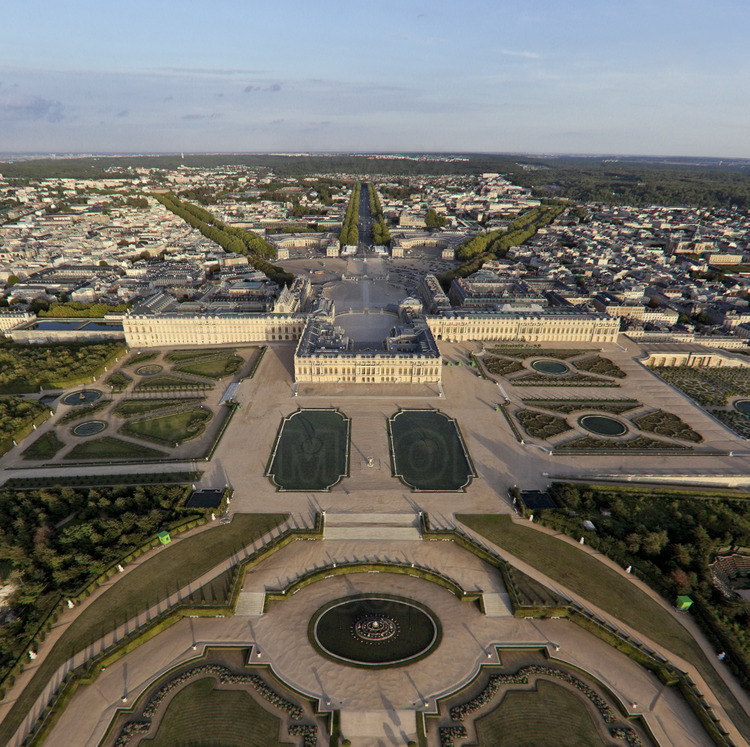 Vue d'ensemble du Château, des jardins et de la ville de Versailles depuis l'ouest. Au premier plan, le bassin de Latone, les Parterres d’eau avec les Parterres d'eau et le Tapis Vert.