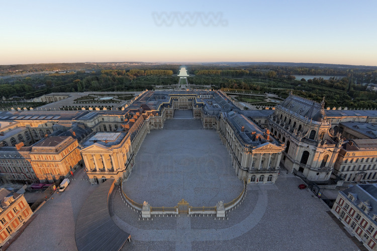Vue d'ensemble de la façade orientale avec, au premier plan, l’entrée du château et la Grille Royale, puis la Cour des Ministres où trône la statue équestre de Louis XIV, la Cour Royale et la Cour de Marbre. En arrière plan, la grande perspective des jardins, donnant sur le Grand Canal.