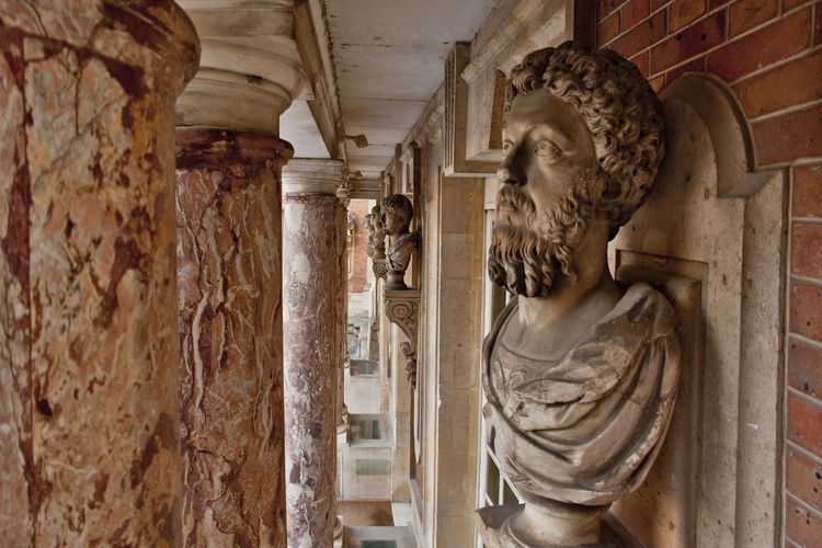 Cour de Marbre. Sous le balcon du Roi, le carrare blanc s'utilise pour les encadrements, faisant ressortir les colonnes de marbre jaspé de blanc et de rouge. A droite, un des quatre-vingt quatre bustes à l’antique des cour Royale et cour de Marbre.