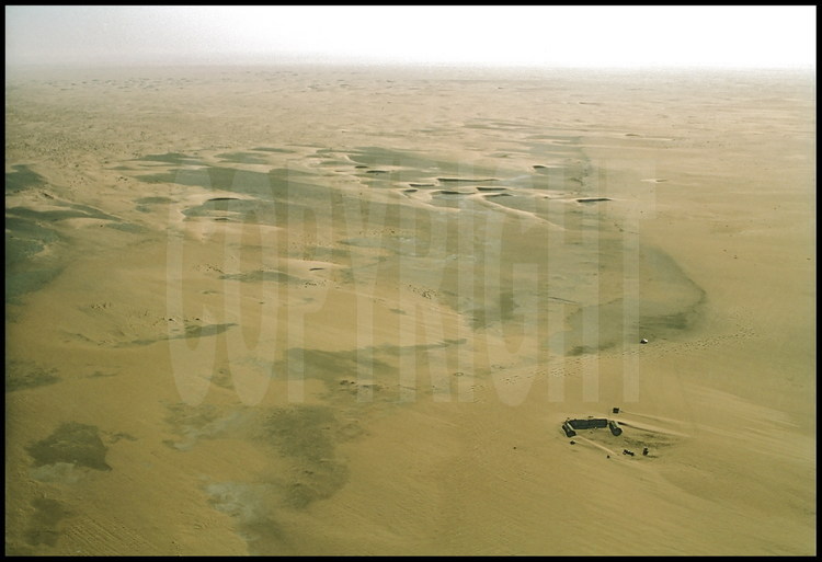 Vue aérienne de l'emplacement du camp des chercheurs, situé dans le désert du Djourab, au beau milieu du Sahara. En foncé, les couches de gisements fossillifères. Les paléontologues - en provenance des Etats Unis, du Royaume Uni, d'Afrique du Sud, du Tchad et de la France- demeurent en autonomie totale pour toute la durée de leur mission (trois ou six semaines).