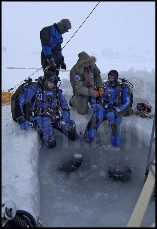 Guislain Bardout et Jérôme Boutin préparent leurs équipements avant de plonger sous la banquise.  Pour minimiser les risques d'accidents spécifiques à la plongée polaire, tous l'équipement hyperbare (1er détendeur, 2ème détendeur, bouteille, etc.) a été doublé.