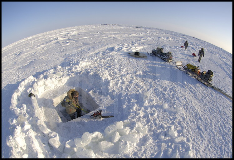 La température polaire oblige les hommes (ici Laurent Stephane) à entretenir le trou creusé dans la glace plusieurs fois par jour.