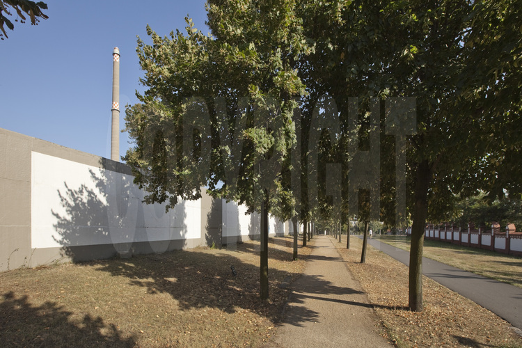 Cimetière de la maison des Invalides (Invalidenfriedhof). Ce site jouxte la berge du Canal de Spandau (Spandauer Schifffahrtskanal). A partir de 1945, le tracé de la ligne de démarcation tel qu'il fut établi par les puissances alliées, traversait cette voie navigable en son milieu. Avec le renforcement, par la RDA, du dispositif frontalier à partir du 13 août 1961, le cimetière Invalidenfriedhof fut partiellement détruit. Des rangées entières de tombes durent céder leur place au No Man's Land. Entre 1973 et 1975, les dernières tombes furent ensevelies, l'aménagement paysager détruit. De même pour la zone à accès réservé, derrière le mur d'arrière-plan: les tombes furent nivelées et le mur du cimetière en briques fut renforcé d'une clôture et intégré dans le dispositif frontalier. Si une infime portion du cimetière survécut à ces transformations, elle le doit aux illustres défunts militaires des guerres de libération de 1813/1815. Un segment du mur d'arrière-plan, long de 180 mètres, et percé en plusieurs endroits, ainsi qu'une portion encore plus longue du chemin de ronde, qui coupaient le cimetière depuis 1975, ont été conservés et classés au patrimoine historique en 1990. Le béton des segments de mur a été restauré en 2003 et repeint avec les motifs qui figuraient autrefois sur la face est du mur d'arrière-plan, c'est-à-dire de rectangles blancs cerclés de gris.