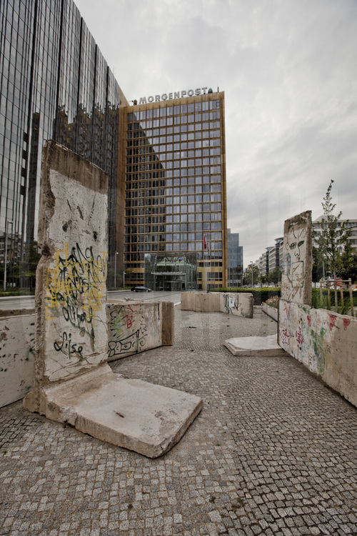 Quarter Axel Springer. Located at the crossroads of Zimmertrasse and Axel Springer Strasse (which takes its name from the building, headquarters of Axel Springer, the latter built along the Wall to the East Germans could see), an artistic work is associated with an earlier building of the Wall. In the background, one of the buildings of the media group. In the downtown district, east of Checkpoint Charlie, the remains of the wall have mostly been sacrificed to the many redevelopment projects. Only the area around the headquarters of the group still has some remnants of the wall.