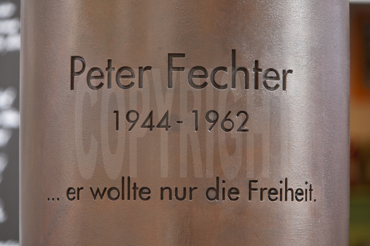 Mémorial Peter Fechter. Le 17 août 1962, Peter Fechter, âgé de 18 ans, fut abattu par les gardes-frontières de RDA alors qu’il essayait de franchir le mur pour gagner Berlin-Ouest. Grièvement blessé, il resta au sol, agonisant au pied du mur sans secours et devint l’une des premières victimes du Mur. La police de Berlin-Ouest n’avait pas le droit d’intervenir et les gardes-frontières des alliés de Checkpoint Charlie n’intervinrent pas non plus. Cet événement provoqua de vives protestations et eu un retentissement médiatique considérable en Allemagne de l’Ouest. Des citoyens ouest-berlinois, qui avaient été témoins du drame, déposèrent des fleurs et des gerbes devant le mur le jour même et créèrent le lieu commémoratif encore présent aujourd’hui. A chaque date anniversaire de la construction du mur (le 13 août), des citoyens et représentants politiques se réunissent ici pour que les victimes du mur de Berlin ne tombent pas dans l’oubli. Le 13 août 1999, la simple croix en bois fut remplacée par cette stèle en bronze, de l’artiste Karl Biedermann. Aujourd’hui encore, une foule anonyme vient fleurir la stèle érigée à sa mémoire, à l’emplacement de sa disparition. Entre 1961 et 1989, plus de 100.000 citoyens de l’ex-RDA ont essayé de fuir leur pays. Plusieurs centaines d’entre eux furent abattus par les gardes-frontières est-allemands ou périrent autrement lors de leurs tentatives de fuite. Le nombre exact de victimes qui trouvèrent la mort à la frontière intra-allemande ou intra-berlinoise n’est toujours pas définitivement arrêtée. Les statistiques diffèrent selon les sources d’informations