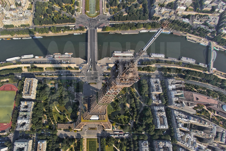 Photographiée avec le ballon-photo, la Tour Eiffel vers 8h du matin, alors que l'équipe des peintre-alpinistes commence son travail sur le monument. Au premier plan, le Champ de Mars, le quai Branly, le pont d'Iéna, la passerelle Debilly et le musée des Arts Premiers. En arrière plan, la Seine et le 16° arrt. de Paris.