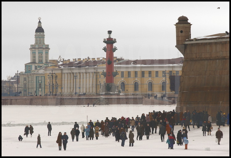 La Néva gelée est, durant tout l'hiver, l'un des lieux favoris des Petersbourgeois pour leur promenade dominicale. En arrière plan, l'île Vassilievski et la Strelka (la pointe) avec, de g. à d., la Kounstkamera( fondée en 1718 et premier musée de Saint Petersbourg), le Musée de la Marine et les Colonnes rostrales. A d., le bastion Narychkine de la forteresse Pierre et Paul.