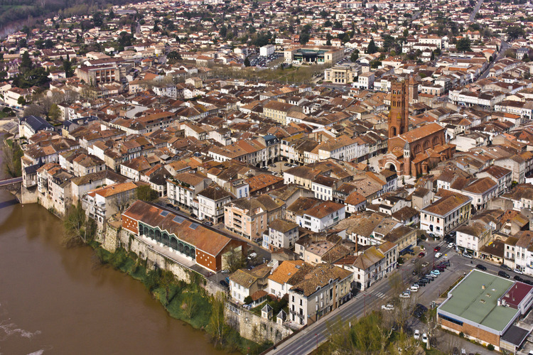 Villeneuve sur Lot : the city center from the south east. Altitude 150 m. In the left foreground, the river Lot and the Halle. In the foreground on the right, rue de la Fraternité. In the background on the right, St. Catherine's Church and behind it, the tower of Paris.