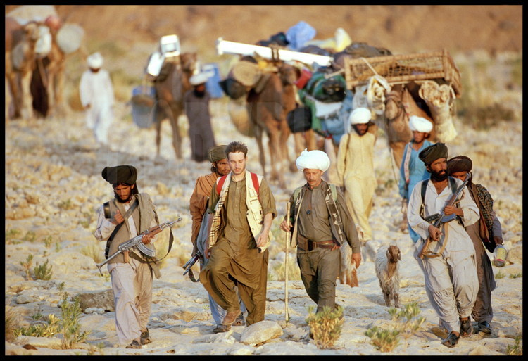 The Journey. Gregoire Métais (left) and Jean Loup Welcomme (right) surrounded by armed Bugti warriors. The team travels by dromedary, the only means of transport adapted to the combination of heavy loads, uneven terrain and a dry climate. vbcrlf<BR>Background: The dromedaries carry food supplies (chickens and live goats), camping gear, and scientific equipment for the month-long expedition.vbcrlf<BR>