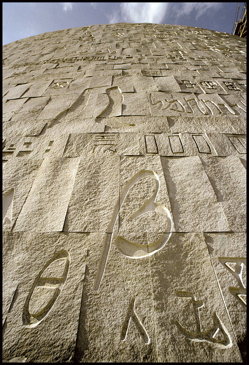 Détail de la façade de la nouvelle Biblioteca Alexandrina. Les 4200 panneaux en granit gris d'Assouan entourant l'édifice sont ornés de tous les symboles que l'humanité a utilisé pour communiquer : écritures du monde entier, notes de musique, nombres et symboles algébriques, codes extraits du langage informatique, etc.