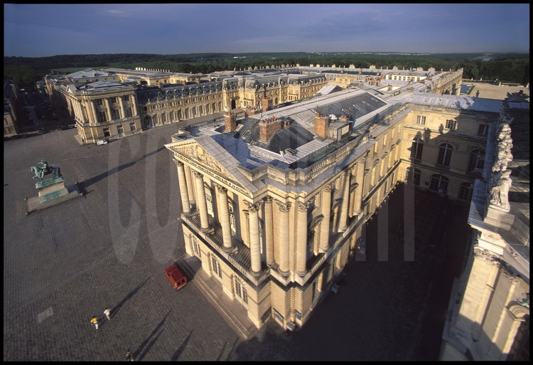 Vue générale aérienne du Château du côté de l’entrée principale. Au premier plan, l’aile Gabriel, à gauche, la statue équestre de Louis XIV dans la Cour des Ministres, au fond, l’aile des Ministres.