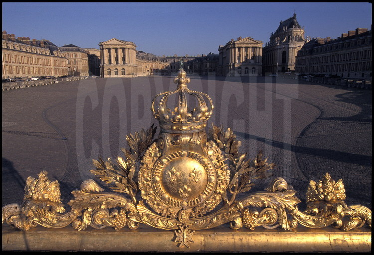 Emblèmes royaux adornant la Grille Royale, à l’entrée du Château : couronne fermée, feuilles de laurier, médaillon et Croix du Saint Esprit.