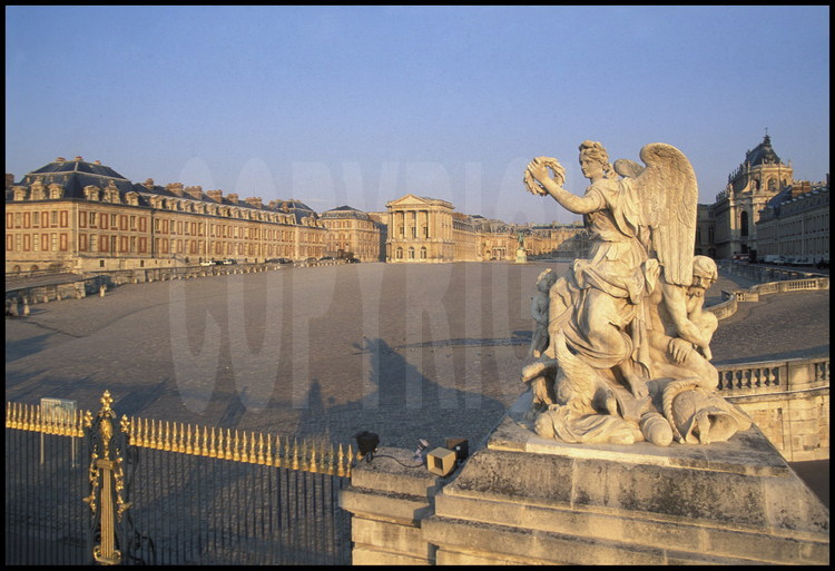 Entrée principale du Château de Versailles. Statue symbolisant la victoire de la France sur l’Espagne réalisée par François Girardon en 1682. En arrière plan à droite, la Chapelle, en face de celle-ci, l’Aile des Ministres.