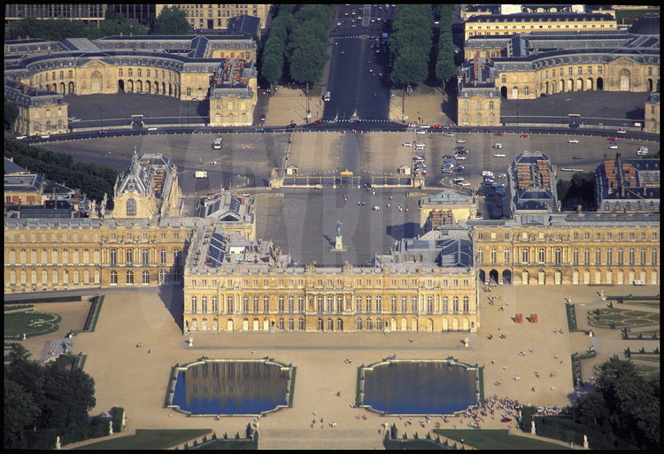 Vue générale de la façade ouest dite « à l’italienne » du Château de Versailles. Au premier plan, les Parterres d’eau. Au second plan, de gauche à droite : l’aile du Nord, le corps central et l’Aile du Midi. Au troisième plan, la Chapelle, la Cour des Ministres et la statue équestre de Louis XIV. En arrière plan, la Grille Royale, les Écuries Royales et l’avenue de Paris.