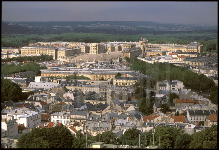 Vue générale du Château de Versailles, façade est. Au premier plan, le quartier historique de Montbauron. Au second plan, les Ecuries Royales. En arrière plan, de gauche à droite : l’Aile des Ministres, la cour des Ministres avec la statue équestre de Louis XIV, la Chapelle, l’Aile du Nord.