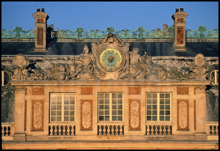 Sur le fronton central de la Cour de Marbre, les fenêtres de la chambre du Roi, surmontées de la grande horloge du Château et de ses éléments sculptés.