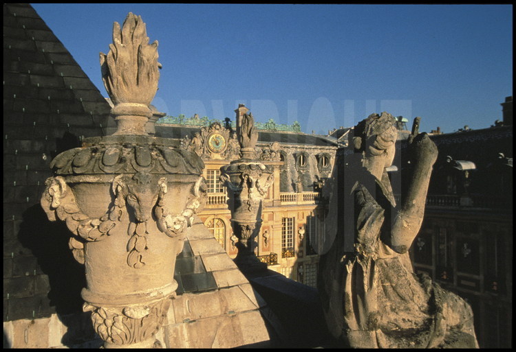 Sur le bourseau de l’Aile du Midi, ensemble de quarante six pots à feu à guirlande et tête de bélier surplombant la Cour de Marbre. à droite , statue de la Gloire, réalisée par Regnaudin en 1680.