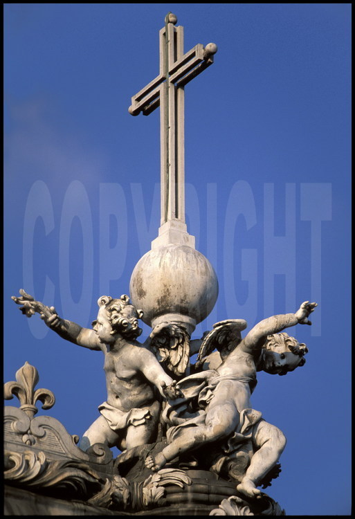 La Chapelle. A l’extrémité est du faîte du toit, statue en plomb représentant trois enfants entourant la Croix.