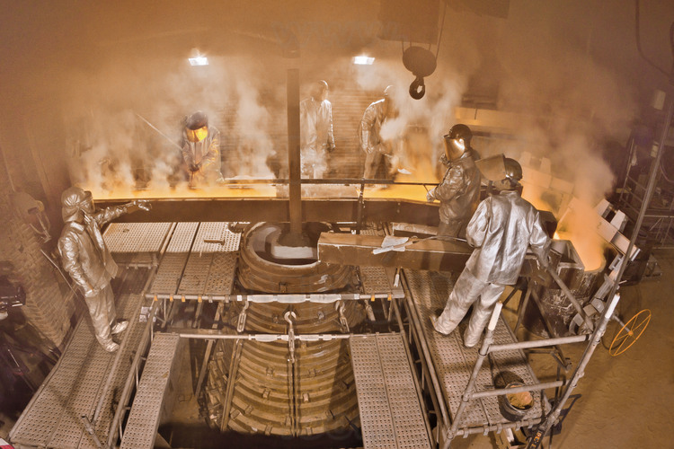 Asten, Netherlands. Royal Eijsbouts foundry, 14 September 2012. Day of casting big bell Mary (note G sharp, 6200 kg). At 5 pm, the casting itself begins : the foundry workers, in protective suit, pour carefully the molten metal into the mold (bottom center). The operation takes about half an hour.
