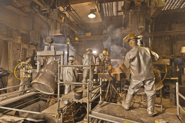  Asten, Netherlands. Royal Eijsbouts foundry, 14 September 2012. Day of casting big bell Mary (note G sharp, 6200 kg). At 5 pm, the casting itself begins : the foundry workers, in protective suit, pour carefully the molten metal into the mold (bottom center). The operation takes about half an hour.