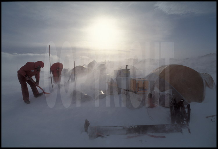 Le blizzard s'est levé d'un coup au camp n° 3. Il durera deux jours. En Antarctique, l'ennemi n° 1 n'est pas le froid mais le vent, car il soulève la neige et l'on perd vote ses repères.  L'obsession est donc de ne pas se perdre, car sans abri dans le blizzard, les chances de survie sont minces. Piquets, fanions et cairns servent de balises dans l'environnement du camp. Le blizzard enseveli sans cesse le camp sous la neige, et l'on passe son temps à pelleter pour ne pas perdre le matériel.