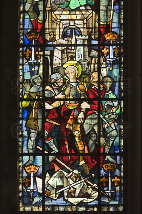 Rouen, où Jeanne d'Arc fut jugée, condamnée et brûlée vive le 30 mai 1431 : Dans la cathédrale de Rouen, vitrail de Jeanne d'Arc faite prisonnière à Compiègne. Jeanne d'Arc, dans sa cuirasse, est saisie par des soldats. Derrière-elle, les murailles de Compiègne. A ses pieds, son étendard et son épée. De chaque côté, en bas, les armes de Jeanne : Épée verticale couronnée, cantonnée de deux fleurs de lys.