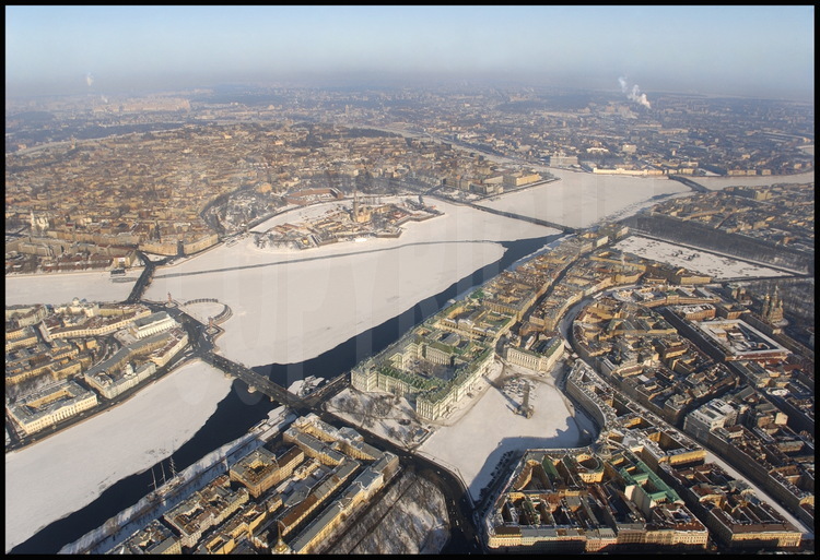 Aerial view of the historical center of the city and of the Neva.  In the 
foreground, from left to right:  the Admiralty, the Hermitage and the Winter Palace, Palace Square and the Alexandre Column, general army headquarters, the Moïka Canal and the Church of our Savior on Spilled Blood.   In the middle, from left to right:  the Strelka(the tip) of Vassilievski island with the Academy of Sciences, the Kounskamera, the Marine Museum, the Rostral Columns, the Peter and Paul Fortress with the cathedral of the same name.  In the background, Petrograd, the city's first neighborhood founded in 1703.