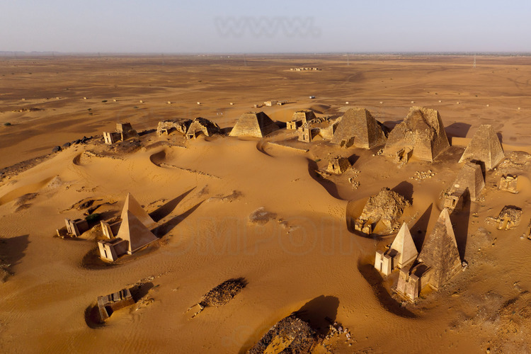 A few kilometers east of the Nile, in the middle of a desert plain, rise strange pyramids, with steep edges. Here, in Meroe, in the heart of Sudan, which were buried the kings of the first known civilization of black Africa. At that time, a rich city extends to the river, with religious monuments, shops, crafts (metalworking, jewelry, pottery ..) while the royal cemetery is located at a distance on hills in the desert. At sunrise, general view of the royal tombs in the cemetery north, by far the largest and best preserved. On the horizon, the green bar of the Nile and cultures.