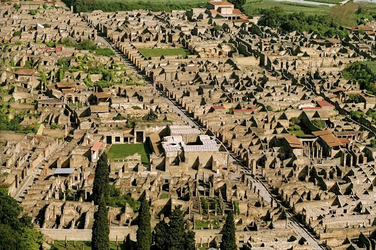 Vue aérienne de Pompéi depuis le Sud. Au centre, la via Stabbiana, qui traverse la cité antique du nord au sud. au premier plan, les thermes de Stabies (blancs). En haut à gauche, la rue tout en courbe du vieux quartier, contrastant avec les artères rectilignes.
