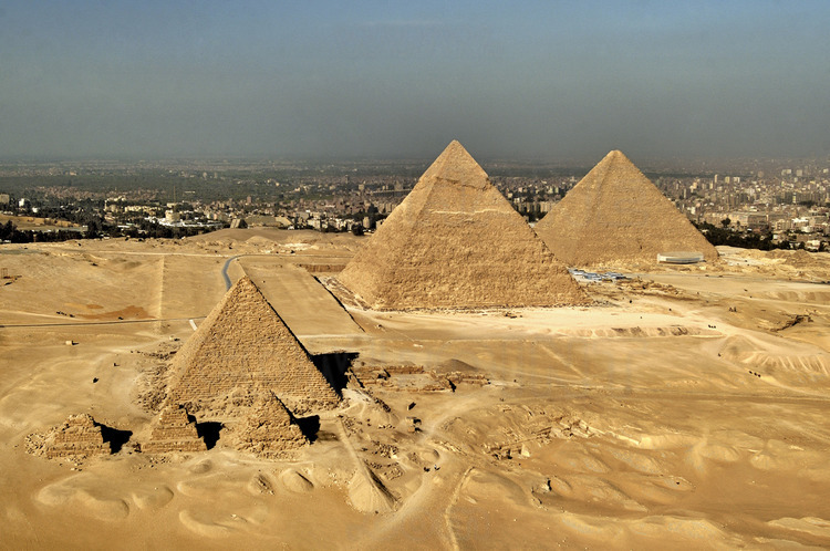 Vue aérienne depuis le désert de Libye, à l’Ouest du Caire : au premier plan, les trois pyramides des reines de Mykérinos. Au second plan, les pyramides de Mykérinos, Khephren et Kheops. A droite de cette dernière, les trois petites pyramides des reines de Kheops. Toutes sont de la IVème dynastie. En arrière plan, la ville du Caire.