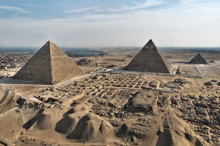 Vue aérienne depuis le Nord du site de Gizeh. Au premier plan, les mastabas occidentaux de la nécropole. Au second plan, les pyramides de Kheops, Khephren et Mykérinos (IVème dynastie). En arrière plan à gauche, la ville du Caire. En arrière plan à droite, le désert de Libye.