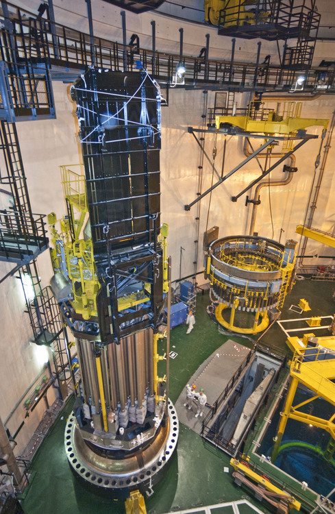 Centrale nucléaire de Cattenom (archives, 2003) : A l'intérieur du bâtiment du réacteur n° 4, les 77 barres de combustible (hautes de 6 mètres) qui surplombaient l’ancien couvercle de la cuve, sont transférées sur le nouveau. La machine visible au second plan servira à revisser le tout sur le cœur.